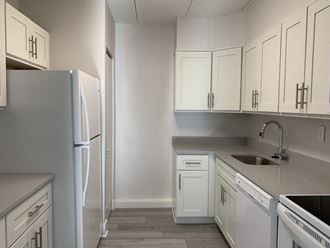 an empty kitchen with white cabinets and white appliances