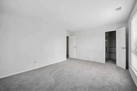 A spacious room with a carpeted floor and white walls.