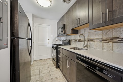 A kitchen with a refrigerator, oven, and sink.