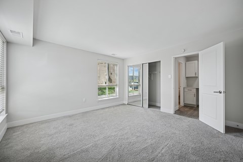 A spacious room with a carpeted floor and a view of the outdoors through a window.