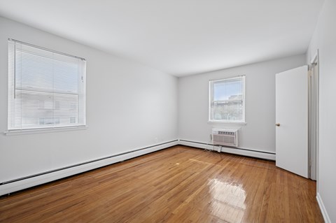 A room with wooden flooring and a window with blinds.