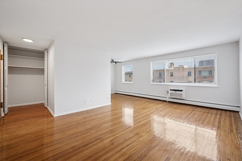 A room with wooden floors and a large window with a view of a building.