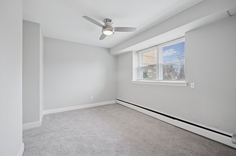 A room with a ceiling fan and a window with blinds.