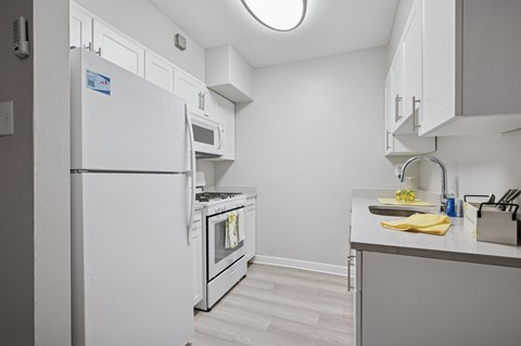 A white refrigerator in a kitchen with a yellow cloth on the counter.