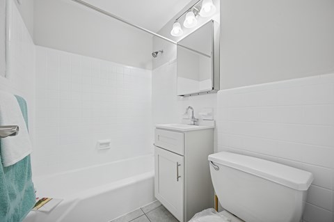 A white bathroom with a tub, sink, and mirror.