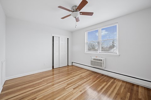 A room with a ceiling fan and a window with blinds.