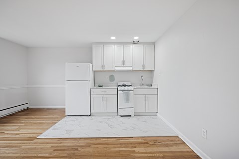 A white kitchen with wooden floors and white appliances.