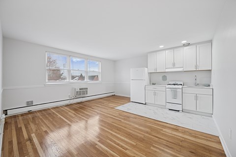 A kitchen with white cabinets and a wooden floor.