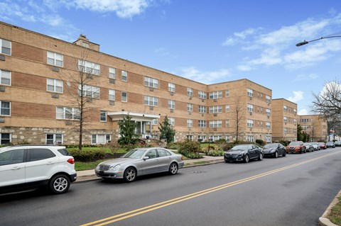Cars parked on the side of a street in front of apartment buildings.