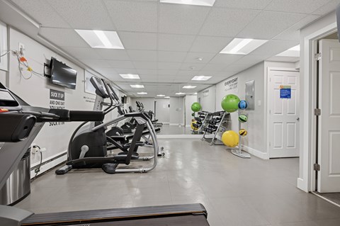 A gym with a treadmill, exercise balls, and a sign that says "START HERE AND GO".