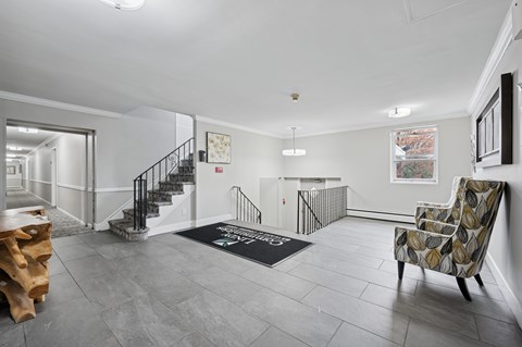 A spacious living room with a grey floor and a wooden chair.