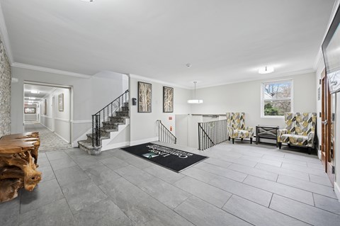 A spacious living room with a grey floor and a black mat on the floor.