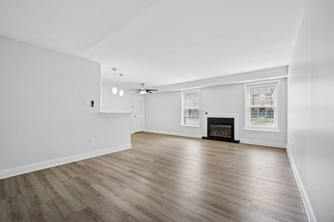 A spacious room with a fireplace and wood flooring.