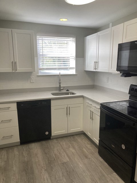 a kitchen with white cabinets and a sink and a window