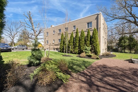 A building with a grey facade is surrounded by trees and shrubs.