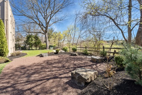 A backyard with a gravel path and a large rock in the middle.
