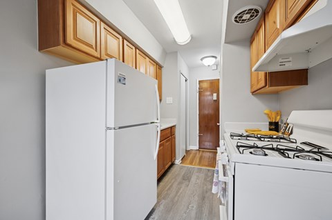 A white refrigerator in a kitchen with wooden cabinets.