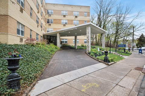 A building with a covered walkway and a yellow bicycle symbol painted on the sidewalk.