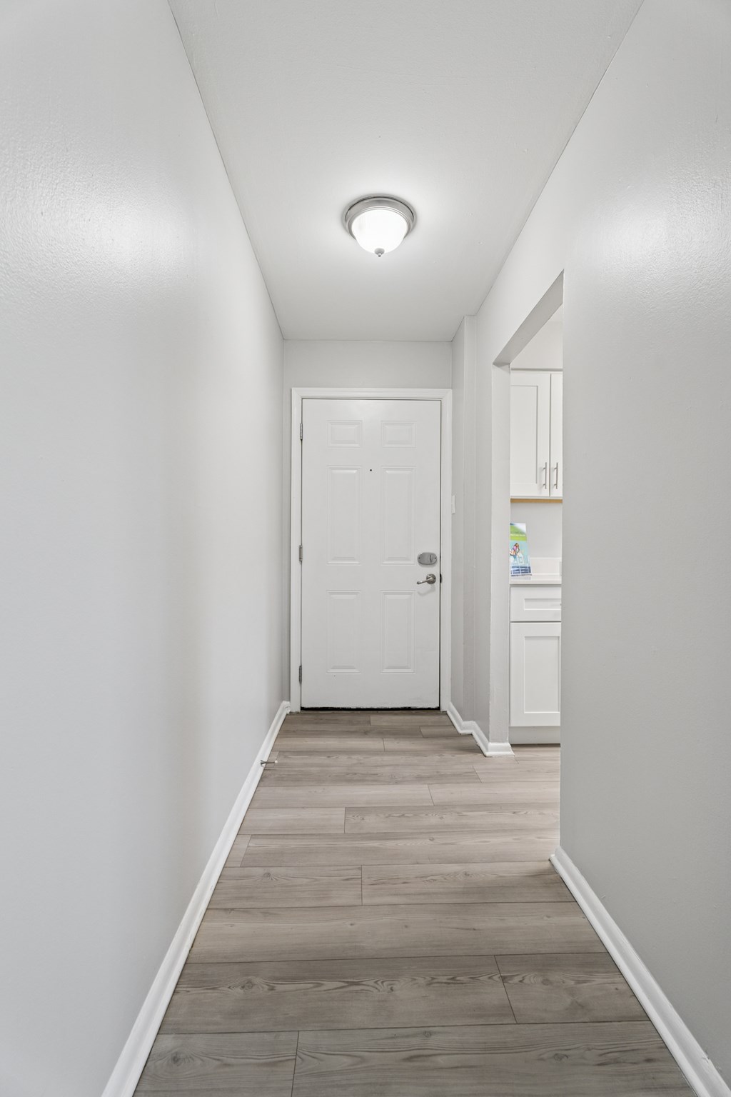 A white door is at the end of a hallway.