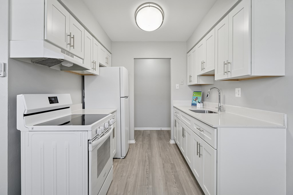 A white kitchen with a stove, oven, and sink.