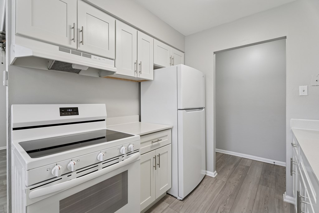 A white kitchen with a stove, oven, and refrigerator.