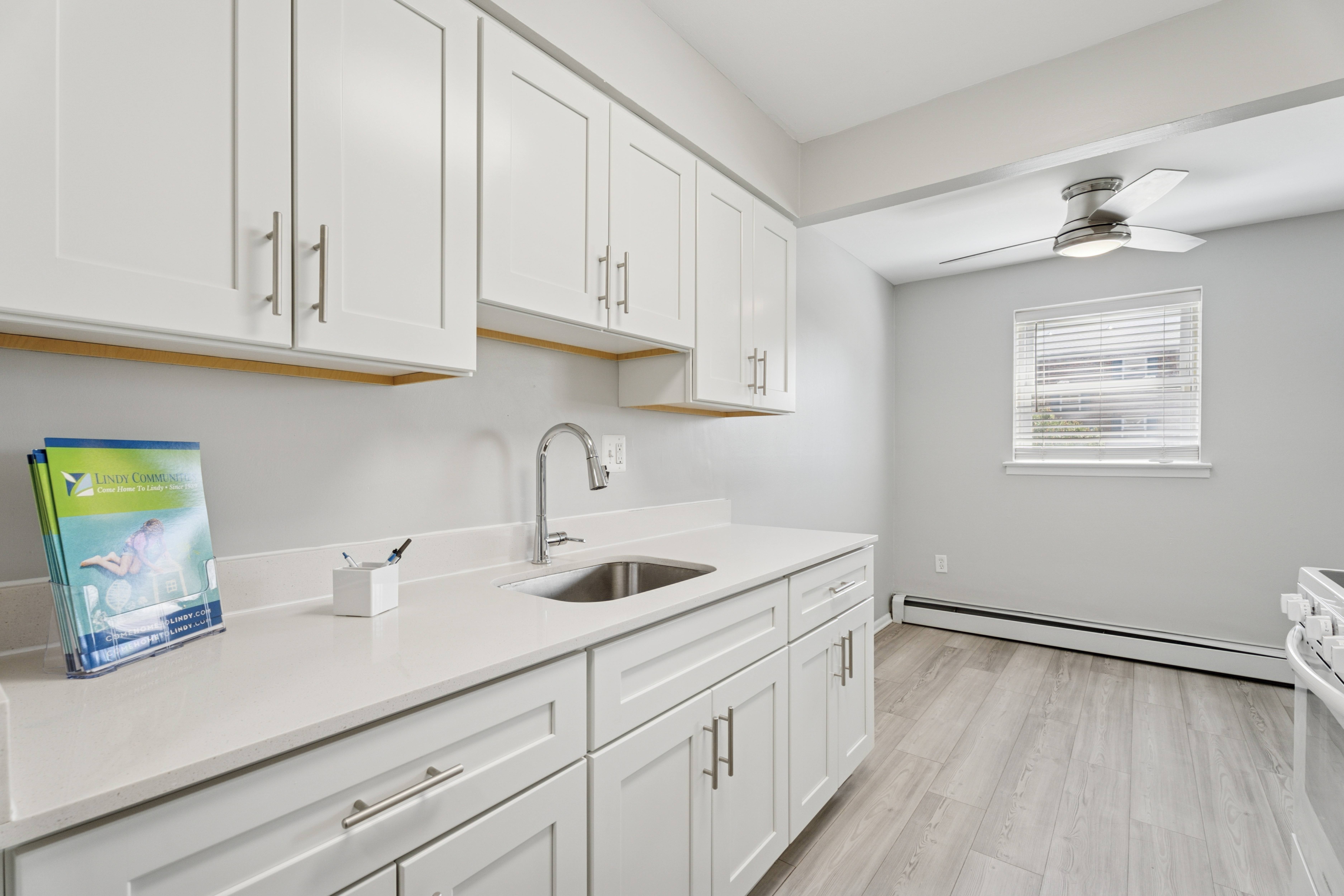 A kitchen with white cabinets and a sink.