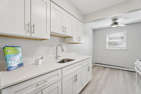 A kitchen with white cabinets and a sink.