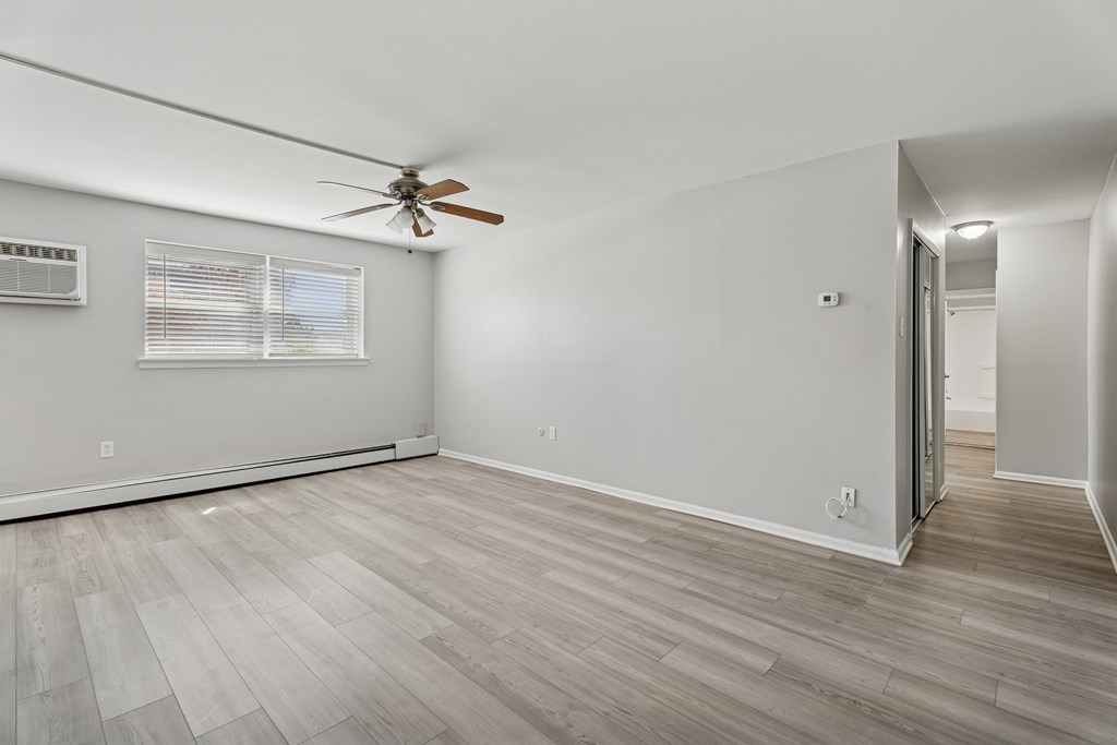 A room with a ceiling fan and a window with blinds.