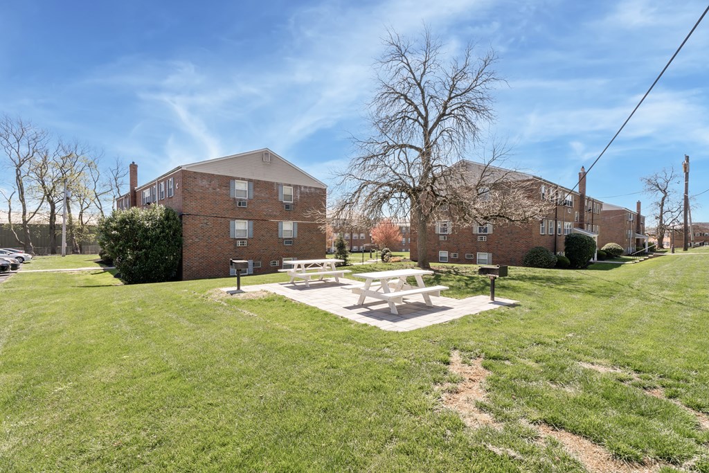 A large grassy area with a picnic table and a building in the background.