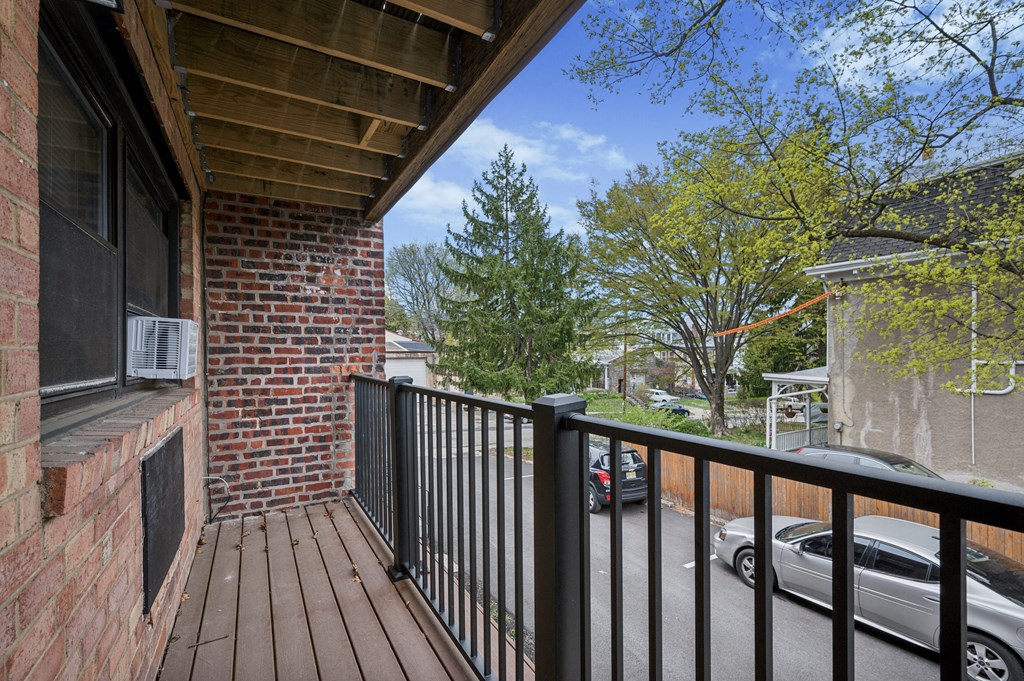A balcony with a black railing and a brick wall.