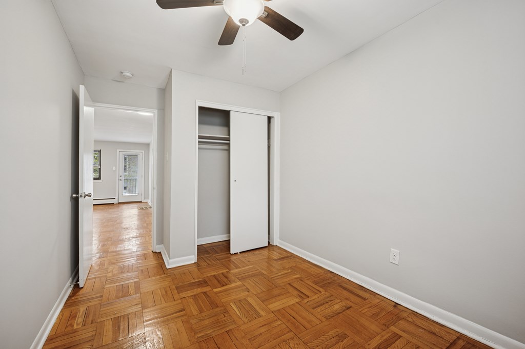 A room with a ceiling fan and wooden flooring.