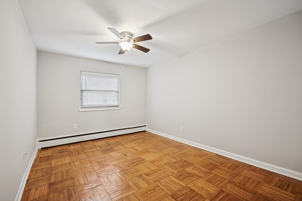 A room with a ceiling fan and wooden flooring.