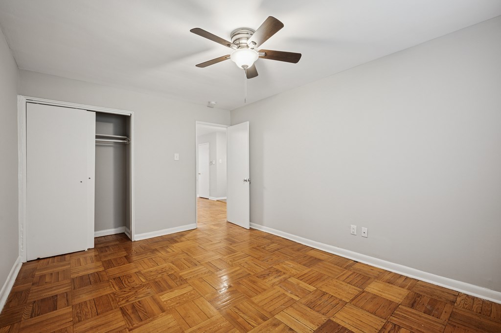 A room with a ceiling fan and wooden floors.