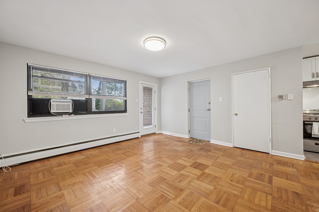 A room with wooden flooring and a window with blinds.