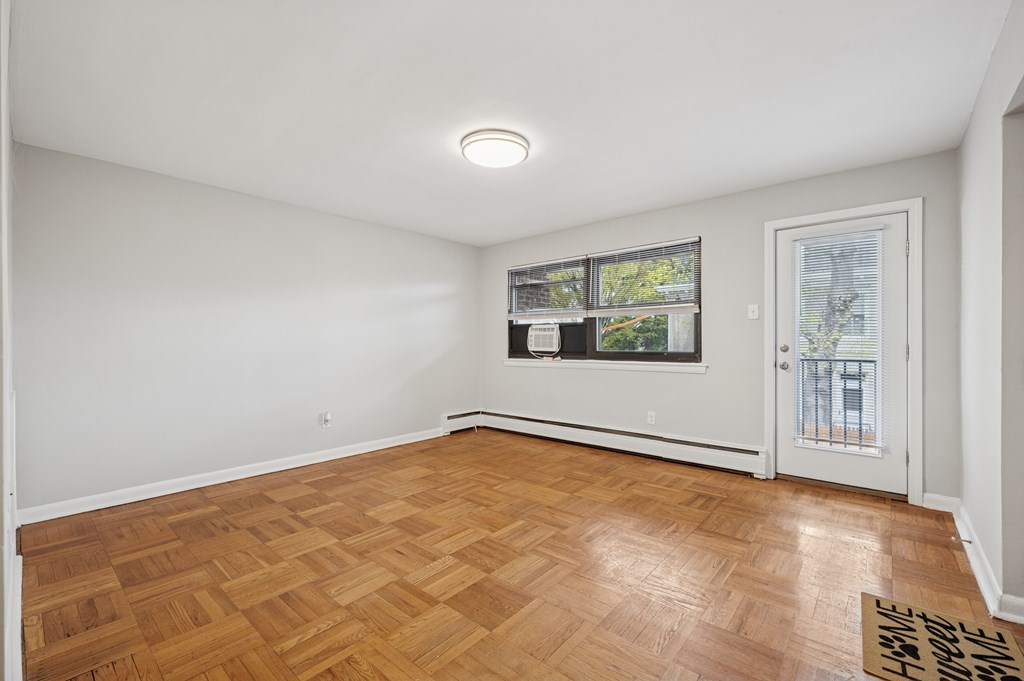 A room with a wooden floor and a door leading outside.