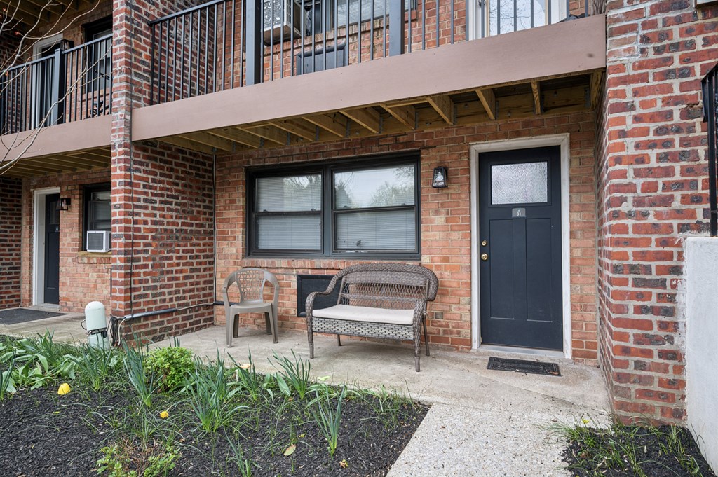 A brick building with a black door and a bench in front.