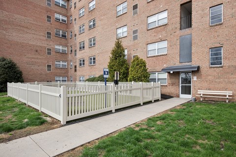 A tall brick building with a white fence in front.
