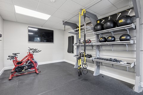 A gym room with a red bike, a yellow pull up bar, and black weight plates.