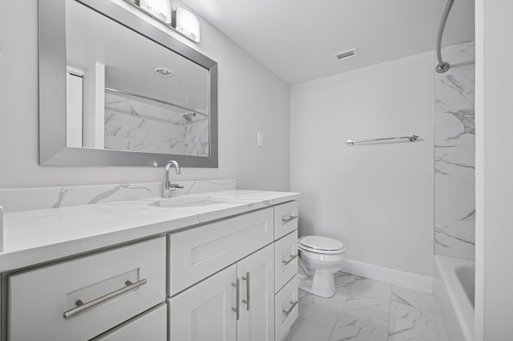 A bathroom with a white toilet, sink, and mirror.