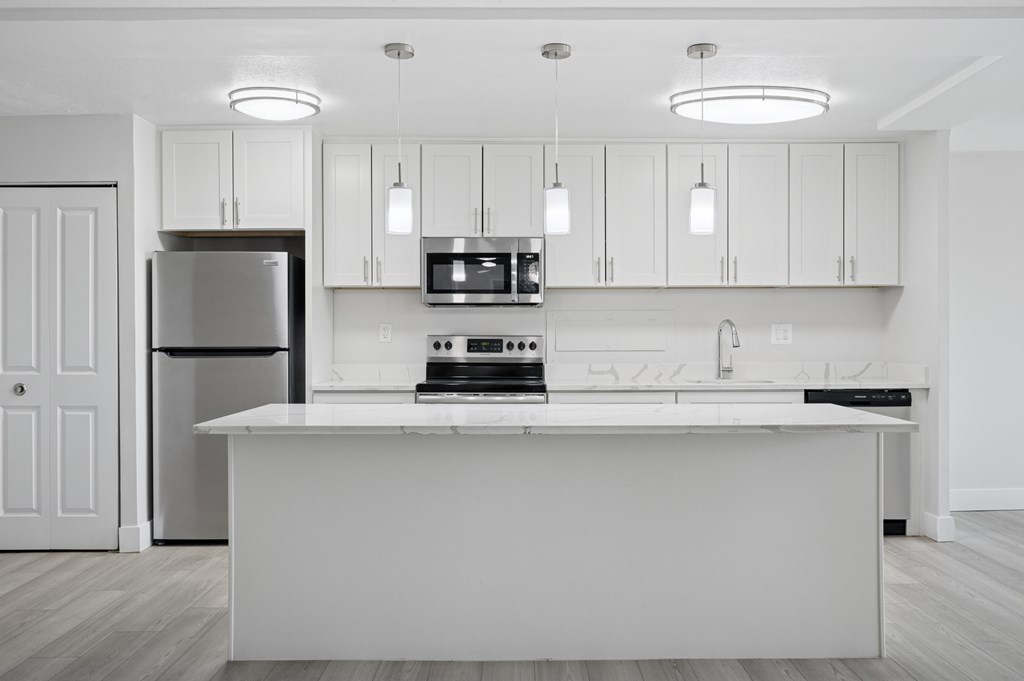 A modern kitchen with white cabinets and appliances.