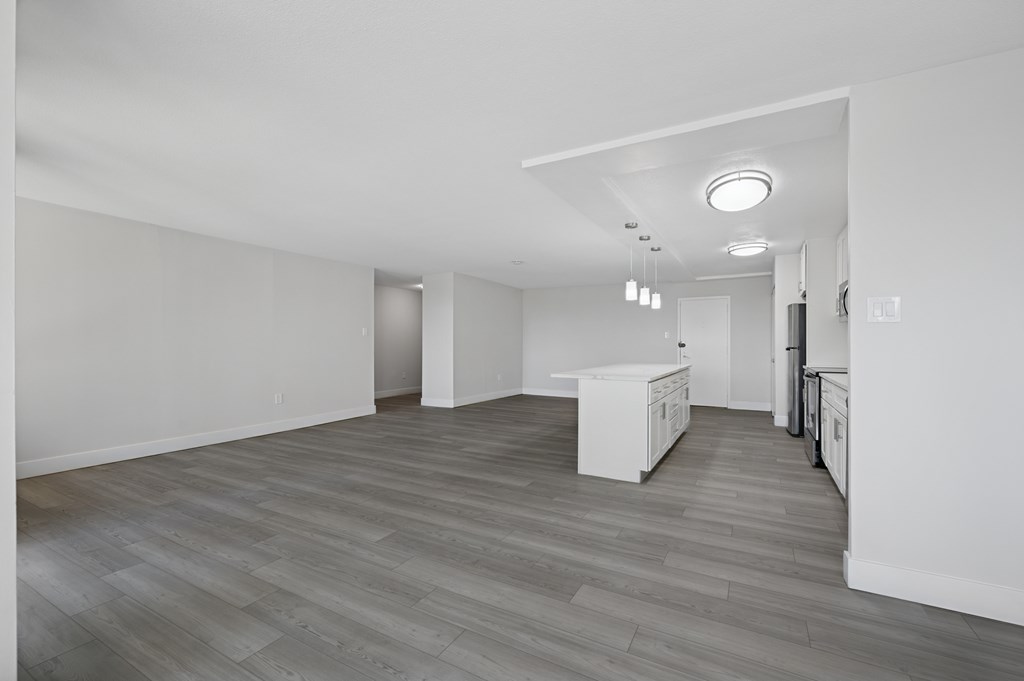 A kitchen with white cabinets and a wooden floor.