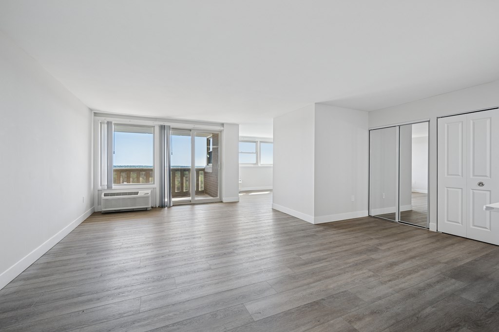 A spacious room with wooden flooring and white walls.