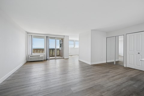 A spacious room with wooden flooring and white walls.