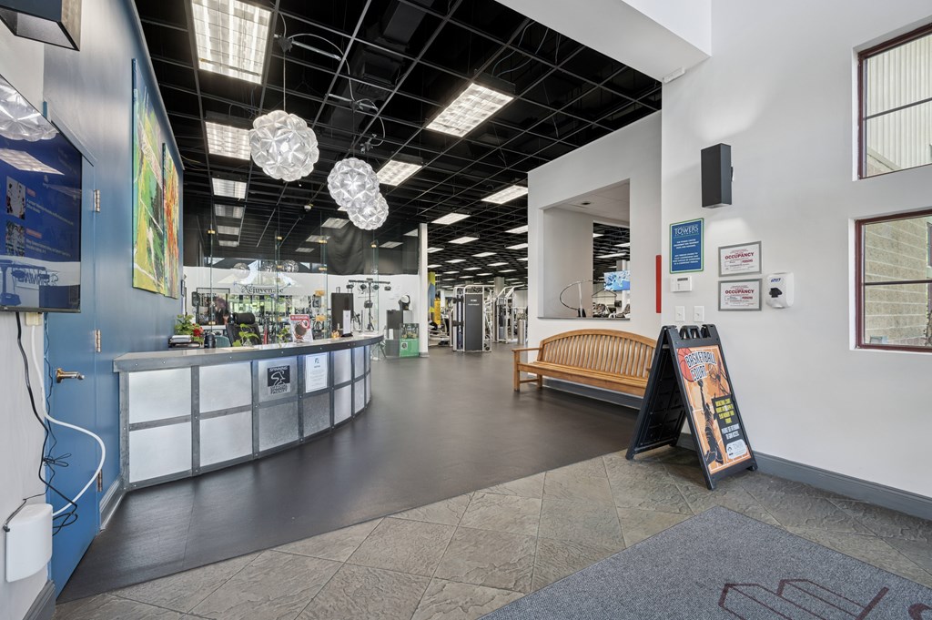 A long hallway with a bench and a sign on the right.