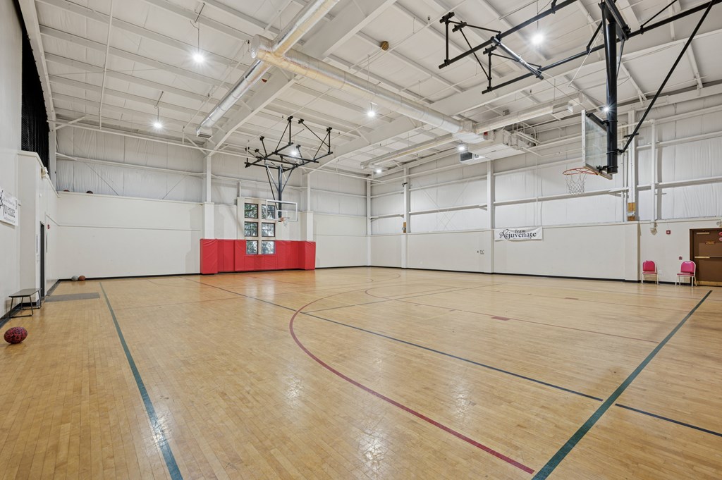 A basketball court with a wooden floor and a basketball hoop.