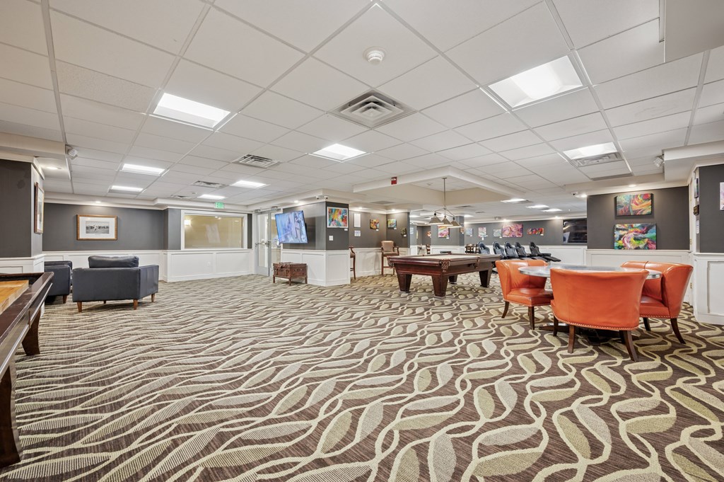 A large room with a patterned carpet and a variety of seating options.