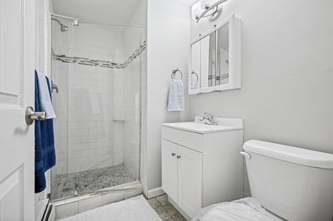 A white bathroom with a blue towel hanging on the door.