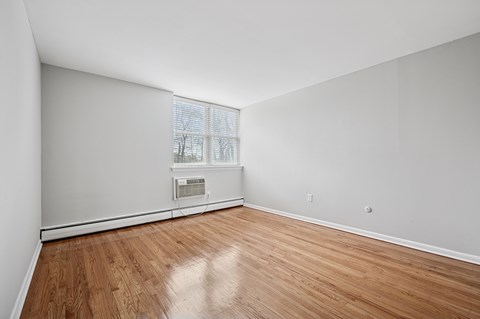 A room with a window and a wood floor.