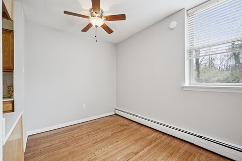 A room with a ceiling fan and a window with blinds.