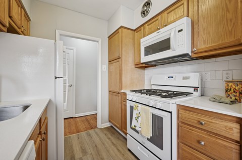 A kitchen with a white refrigerator, white stove, and wooden cabinets.